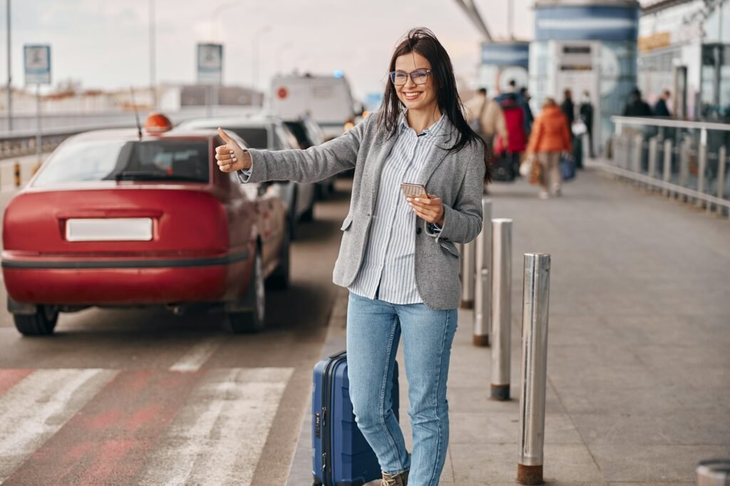 Happy caucasian woman traveller in airport terminal is taking a taxi