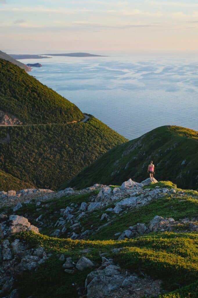 Hiker on rocky outcrop, Cape Breton, Nova Scotia, Canada